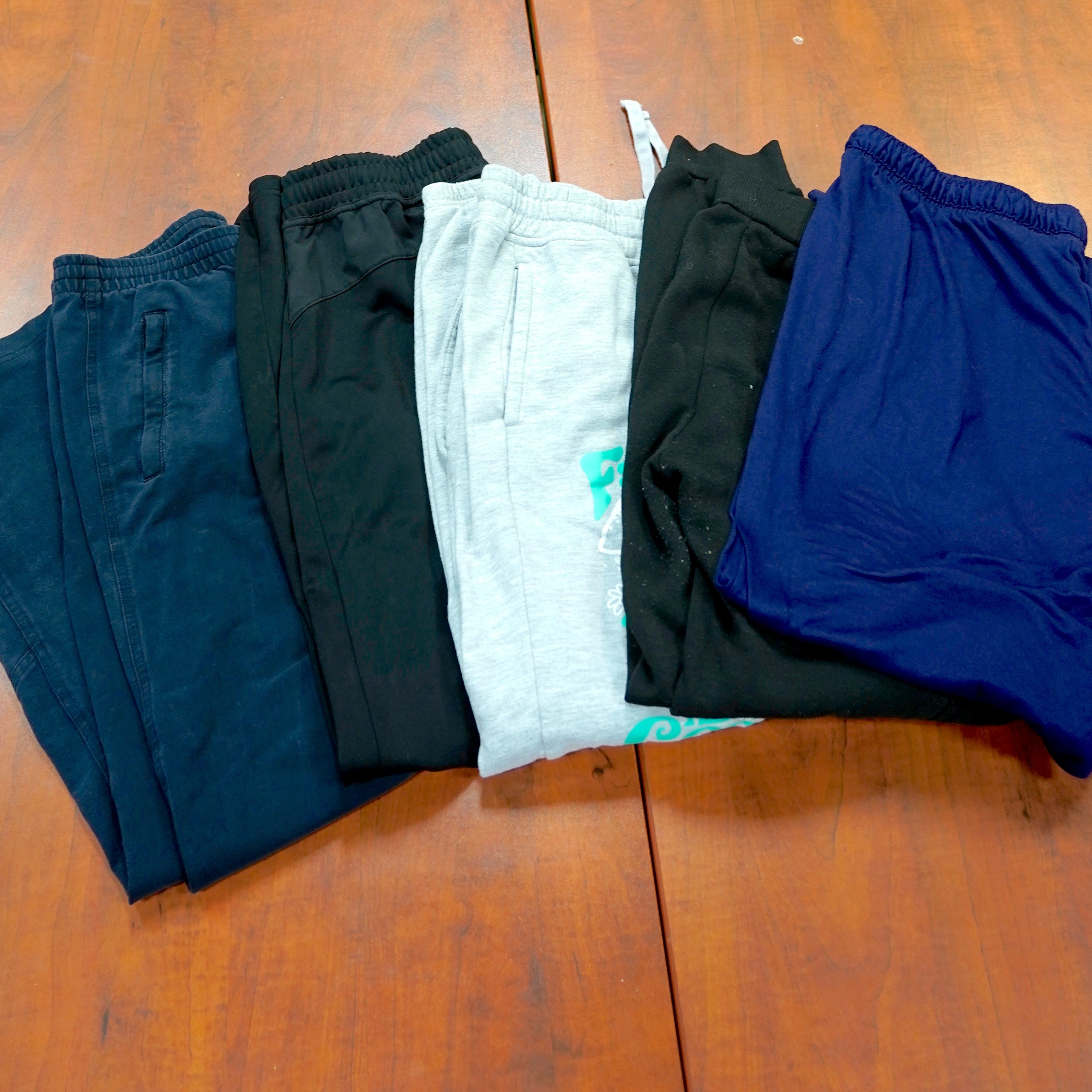 Five pairs of sweatpants in gray, blue and black.