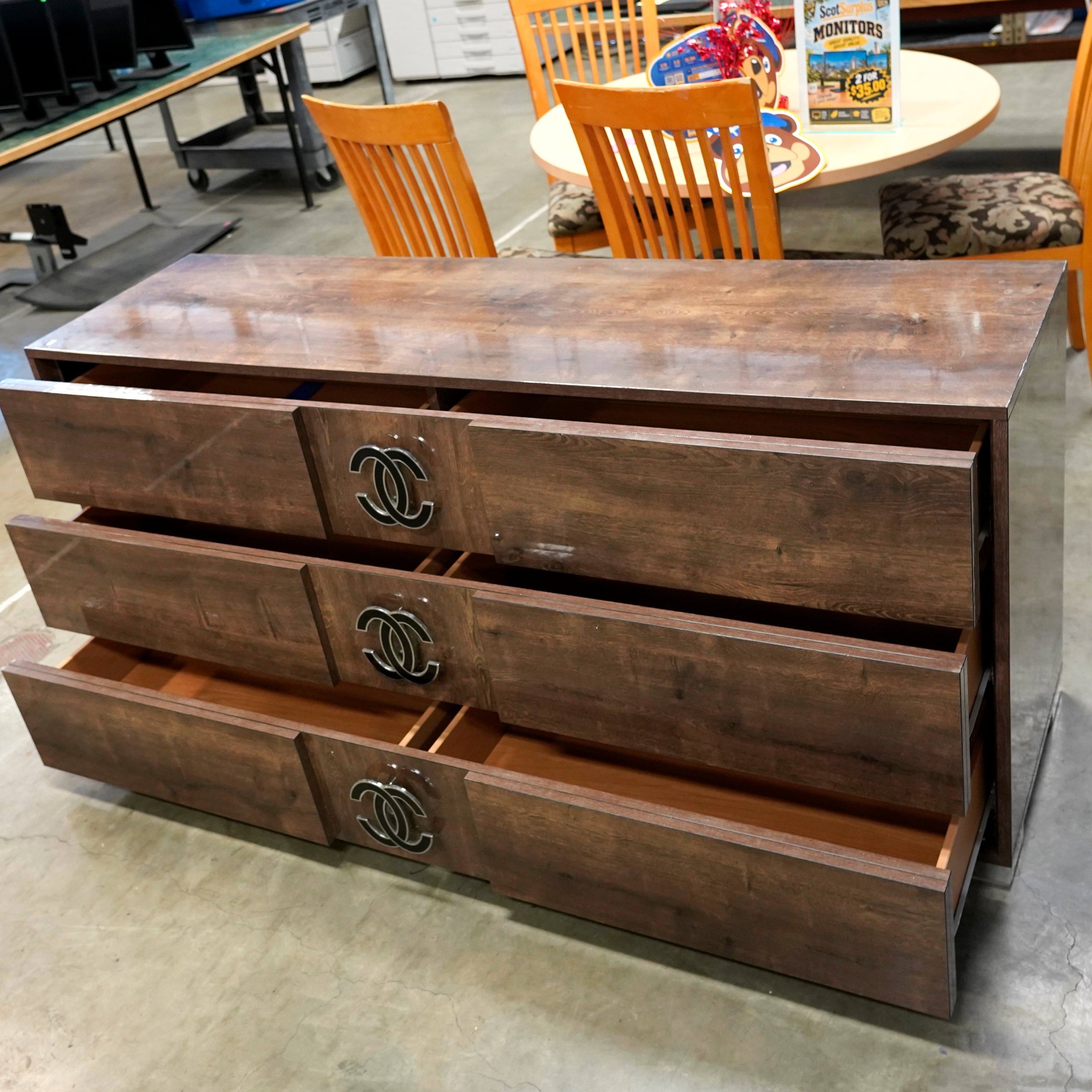 A 3-drawer wooden dresser with divided drawers, interlocking Cs pull handles and chrome feet.