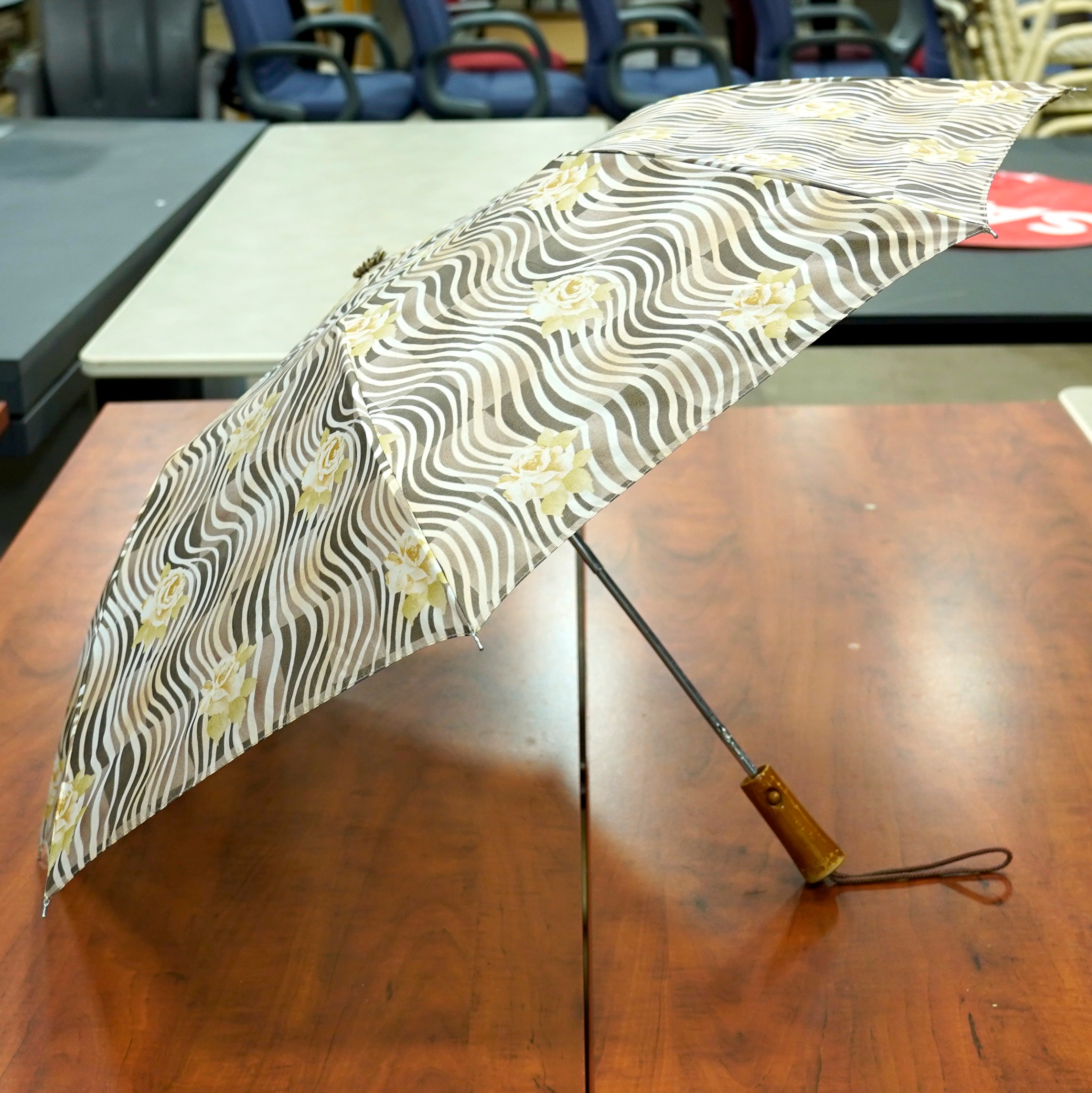 An open umbrella with a black and gray design featuring a rose motif.