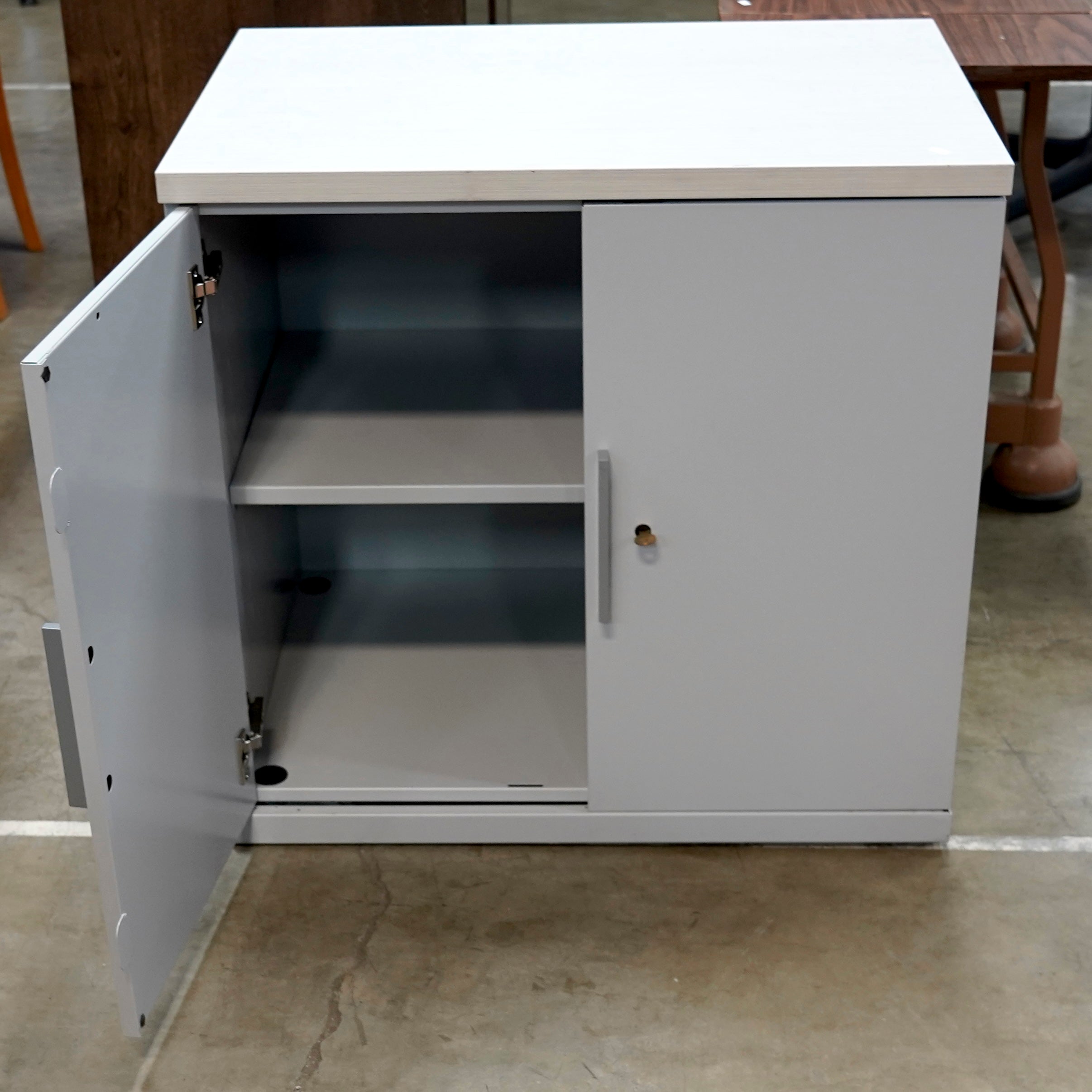 One off-white 2-shelf metal cabinet with key.