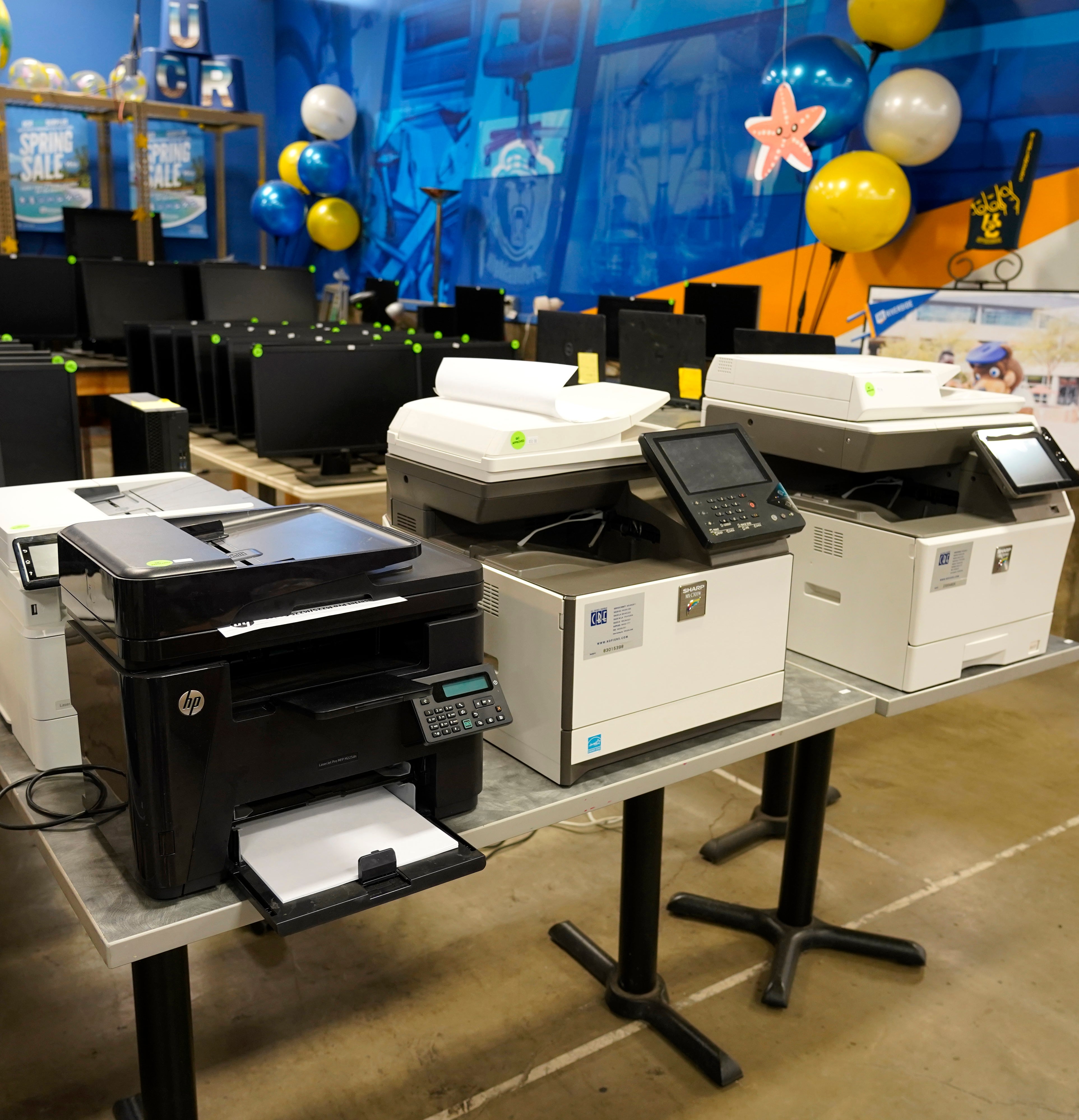 5 Sharp and HP desktop printers on a table.