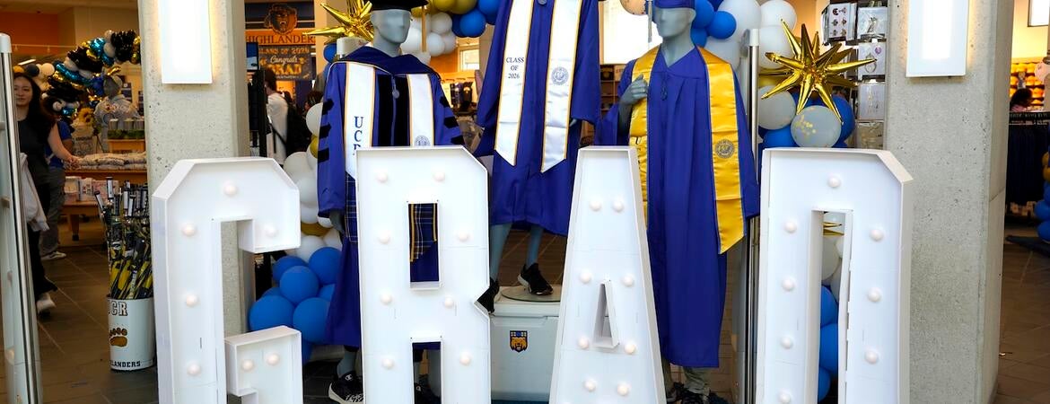 Light-up letters that spell out GRAD with blue graduation robes.