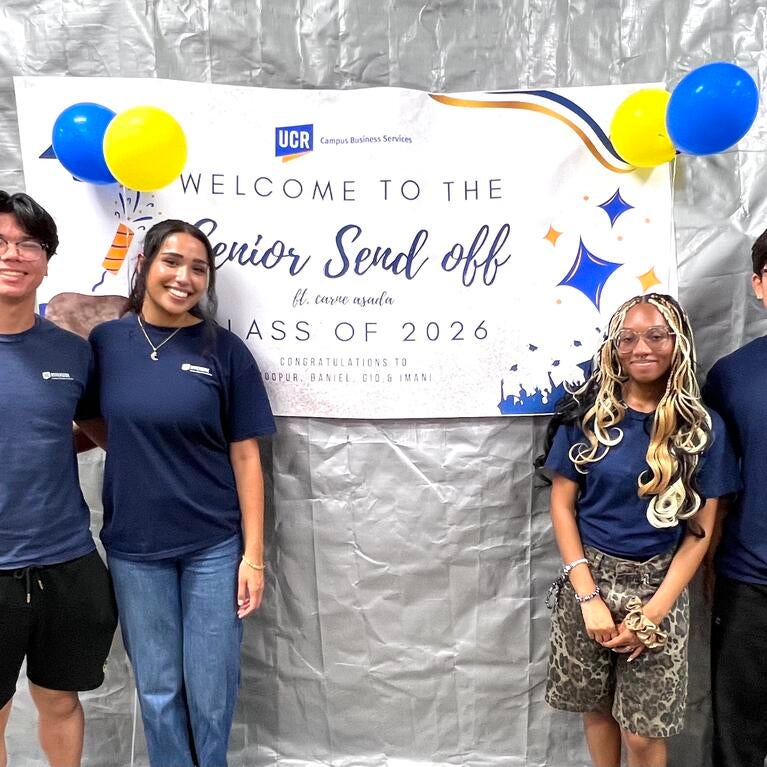 Four graduating CBS student workers pose in front of a "Senior Send Off" banner.