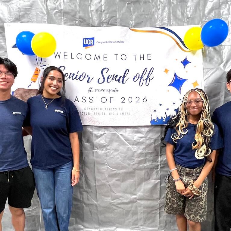 Four graduating CBS student workers pose in front of a "Senior Send Off" banner.