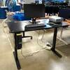 Electronic standing desk with computer setup and projector.