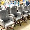 Ten rolling chairs with gray fabric and wood-toned bottoms